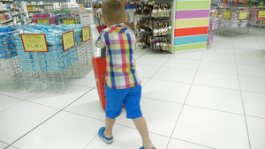 慢动作拍摄一个男孩在超市里推着购物车36秒视频