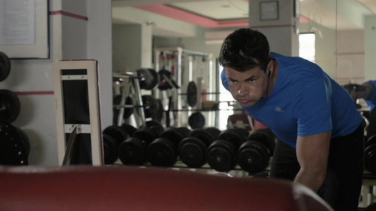 年轻的肌肉男在健身房努力用哑铃做运动视频