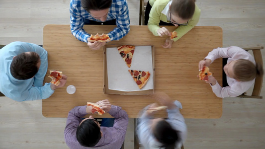 一群年轻朋友围着桌子在吃比萨饼视频