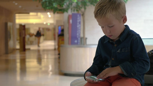 小男孩在购物中心看着智能手机上的照片26秒视频