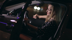 夜晚美丽的女人坐在车内驾驶座上开着门听音乐26秒视频