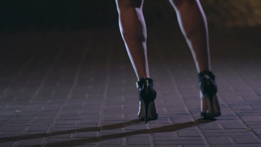 夜晚穿着高跟鞋在城市道路上跳舞的女孩腿部特写视频