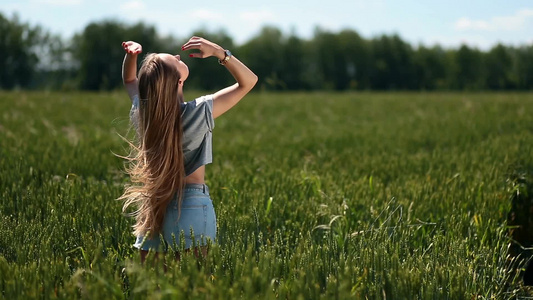 年轻女子在绿色麦田里迎风拨动头发视频
