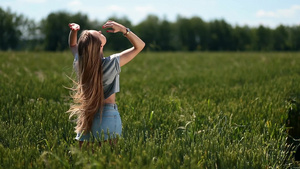 年轻女子在绿色麦田里迎风拨动头发25秒视频