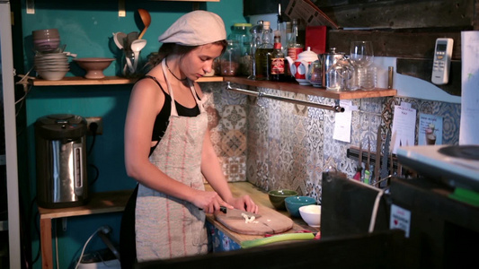 美丽的年轻女厨师在砧板上切大蒜视频