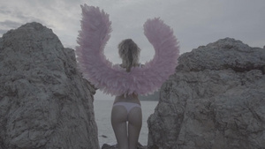 年轻美女穿着天使的翅膀站在岩石之间6秒视频