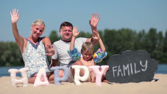 在暑假里快乐的家庭爸爸妈妈和儿子坐在海滩上拍照视频