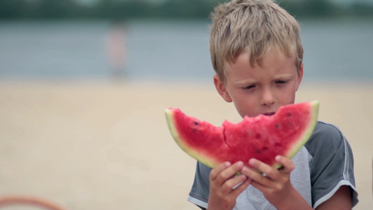 小男孩在海滩上吃美味的西瓜视频