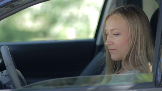 年轻女性坐在驾驶座上的侧视图视频