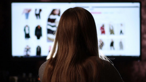坐在电脑前进行网上购物的长发女孩的背影18秒视频