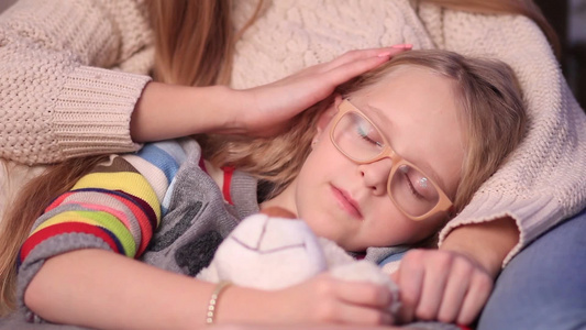 戴着眼镜的小女孩在妈妈的怀抱里睡着了视频