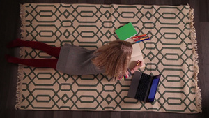 可爱的女孩躺在地板上的地毯上用笔记本电脑做作业10秒视频