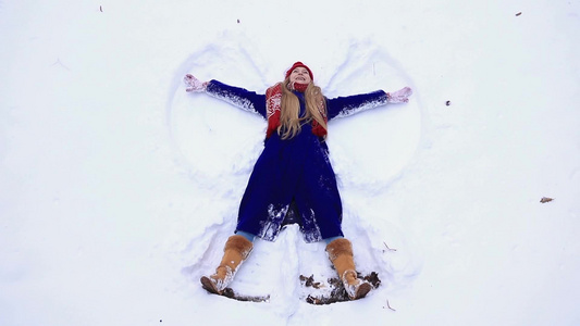 年轻快乐的女人躺在雪地上视频