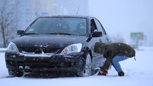 给轿车车轮铲雪的女人16秒视频