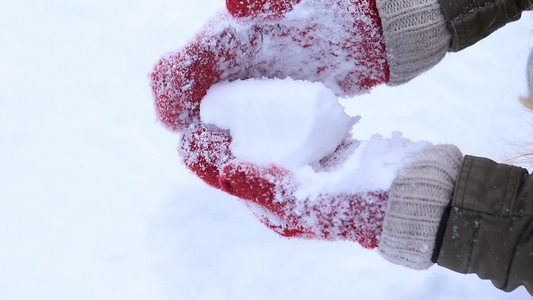  女人的手戴着羊毛手套做雪球视频