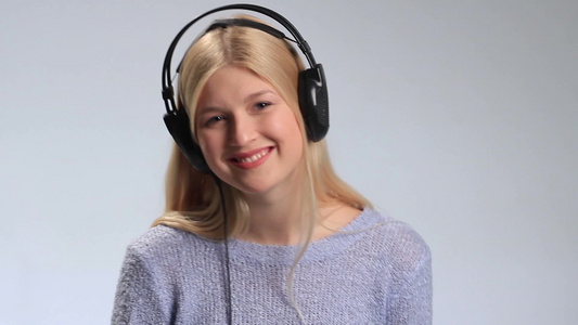 年轻漂亮的女孩戴着耳机跟着音乐摇摆视频