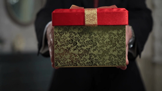 中年男子穿着正式西装拿着一个礼品盒视频