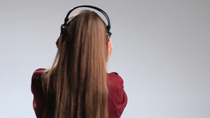 年轻的金色长发女人背影戴着耳机听音乐身体跟着音乐节奏摇摆15秒视频