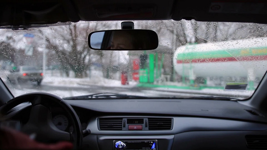 年轻的女司机在冬天开车去加油站加油视频