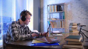 英俊的时尚自由职业者戴着耳机听着音乐使用笔记本电脑工作14秒视频