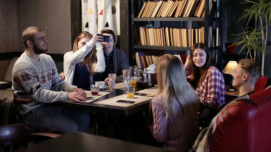 一群男女朋友一起在咖啡馆里享受美好的时光并相互交流视频