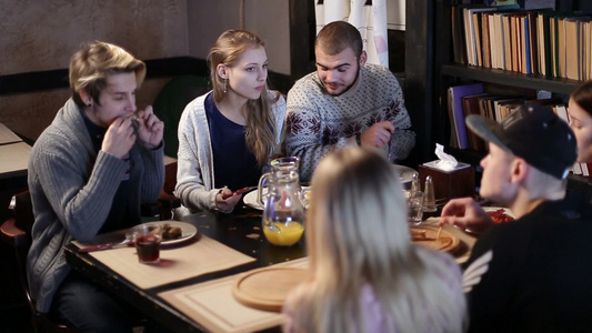 一群年轻人在咖啡馆一边吃饭一边聊天视频