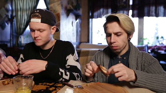 两个年轻人在餐厅吃美味的烤鸡翅视频