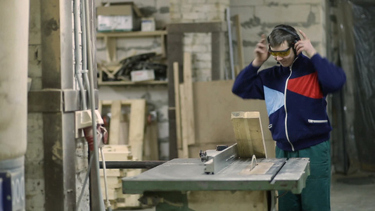木材工匠戴着安全护目镜和耳罩在车间用圆锯切割木板视频