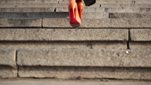 穿着橙色的高跟鞋行走在城市的石阶上视频