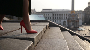 穿着绿色大衣和橙色高跟鞋的女性优雅地走在城市的石头楼梯上13秒视频