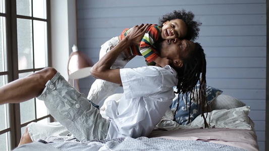 英俊的非裔美国父亲在床上和儿子玩耍视频