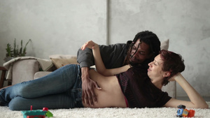 一对相爱的夫妇幸福地躺在客厅地板上丈夫抚摸着妻子怀孕的肚子一起期待着未来12秒视频