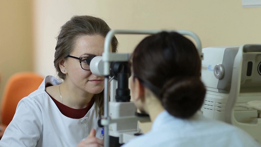 在眼科诊所女性验光师与非接触眼压计检查患者的眼压视频