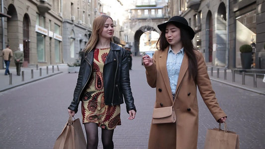 两个迷人的女孩提着购物袋逛街视频