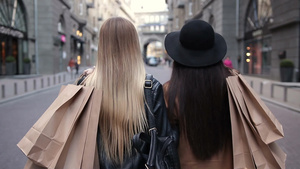 在街道上行走的两个有吸引力的背着购物袋的女孩26秒视频