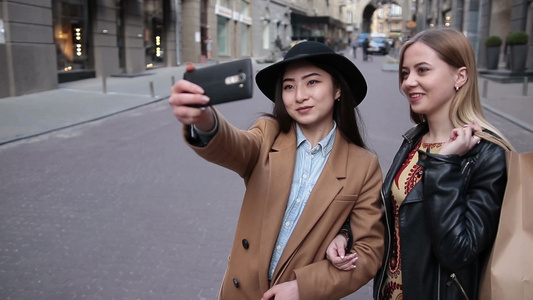 提购物袋的两个女孩在城市街道自拍视频