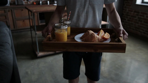 男士托盘上拿着橙汁和牛角面包10秒视频