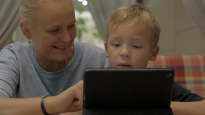 在咖啡馆母亲陪着儿子一起用平板电脑进行线上学习31秒视频