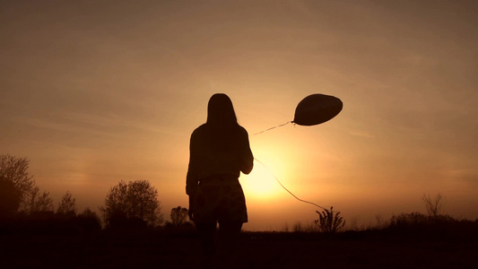 年轻女孩拿着气球进入夕阳的光辉[二十多岁]视频