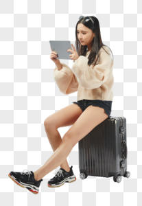 年轻女孩坐在行李箱上玩平板电脑高清图片