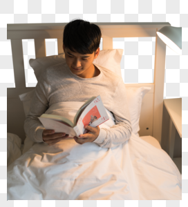 晚上坐在床头看书的年轻男性图片
