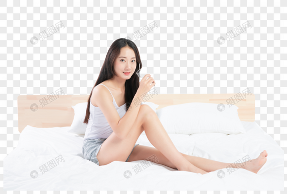 美女坐在床上喝水图片