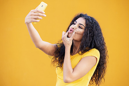 有趣的阿拉伯女人用智能手机拍自拍照片卷发女性年轻的阿拉伯女人用智能手机自拍图片