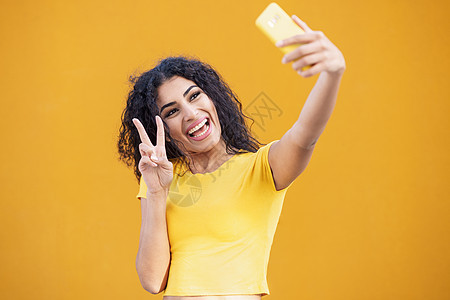 有趣的阿拉伯女人用智能手机拍自拍照片卷发女性年轻的阿拉伯女人用智能手机自拍图片