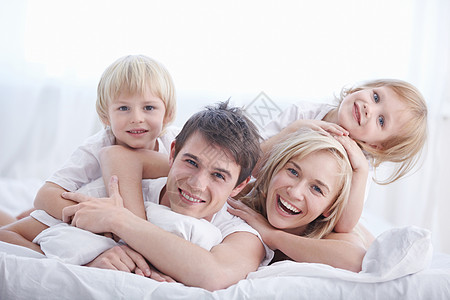 卧室里白色床上的幸福家庭背景图片