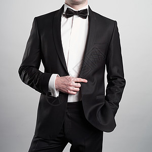 时尚男人的照片,穿着优雅的黑色西装领带时尚的年轻模特姿势摄影工作室奢华的夜晚吸烟与白色衬衫图片