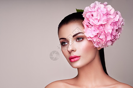 波特雷模型装饰了大粉红色的花头上黑发女人,化妆豪华完美的皮肤睫毛化妆品眼影图片