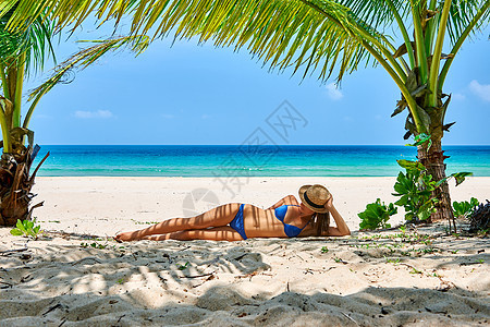 棕榈树下海滩上的女人身上有叶影图片