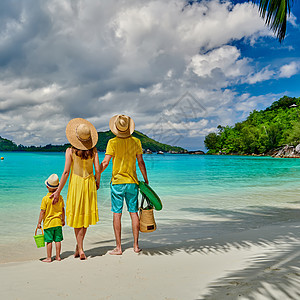 海滩上的家人,穿着黄色衣服的年轻夫妇三岁的男孩塞舌尔的暑假马海港图片