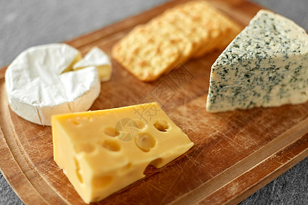 食物饮食同种类的奶酪咸饼干木制切割板上木板上有同的奶酪饼干图片